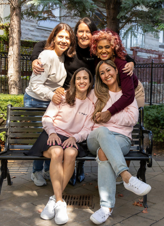 Women sitting together wearing HeartWear Co. comfort clothing, representing emotional healing, community, and self care.