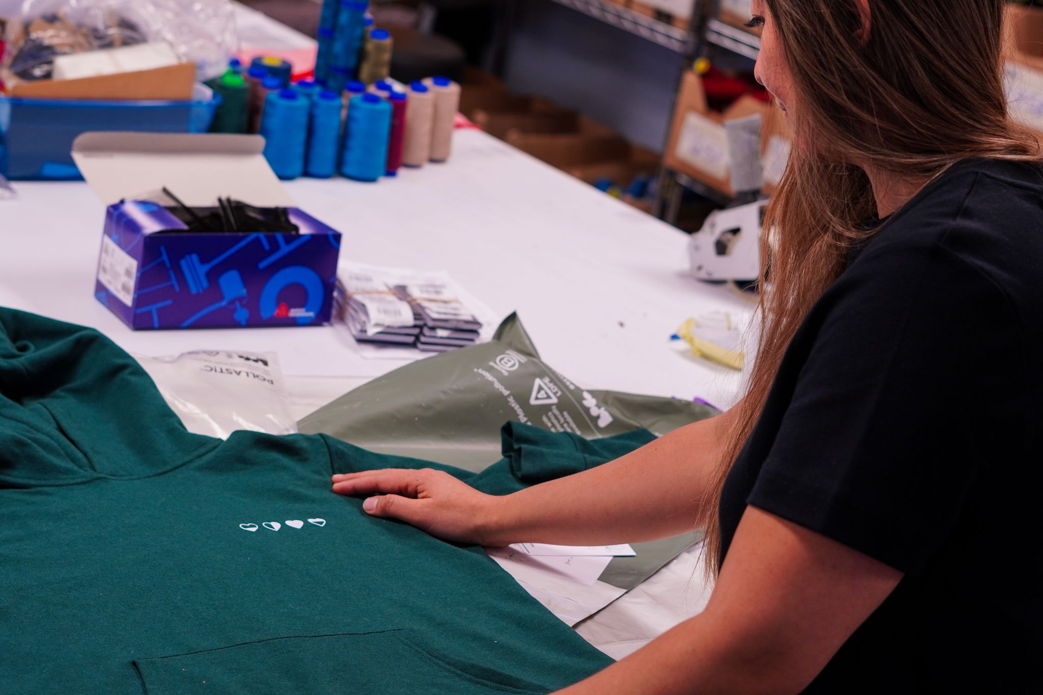 Co-founder folding a Healing Hearts hoodie in the HeartWear factory — handmade in Canada using sustainable materials