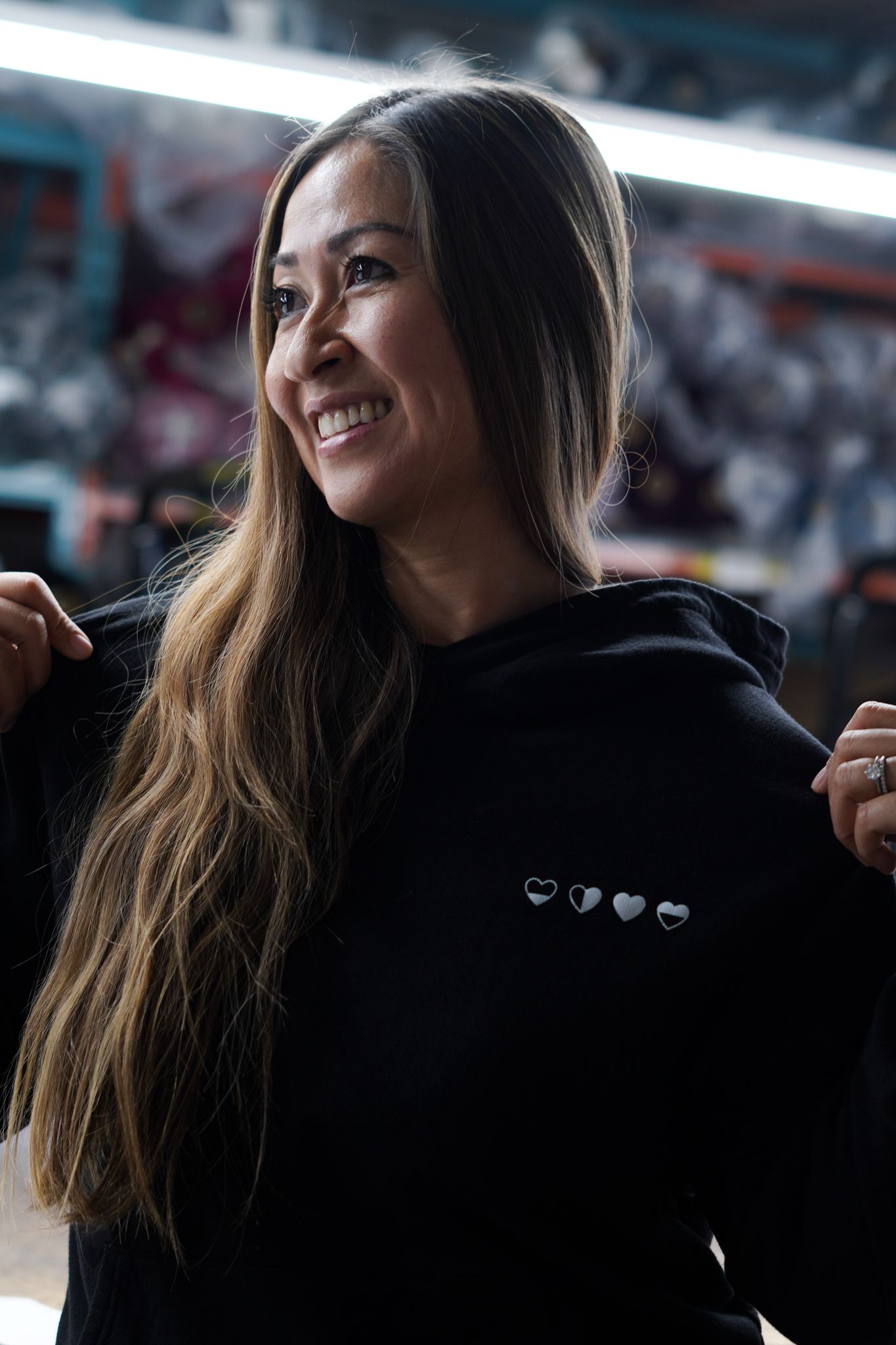 Founder wearing Healing Hearts black hoodie, smiling — sustainable grief and healing apparel
