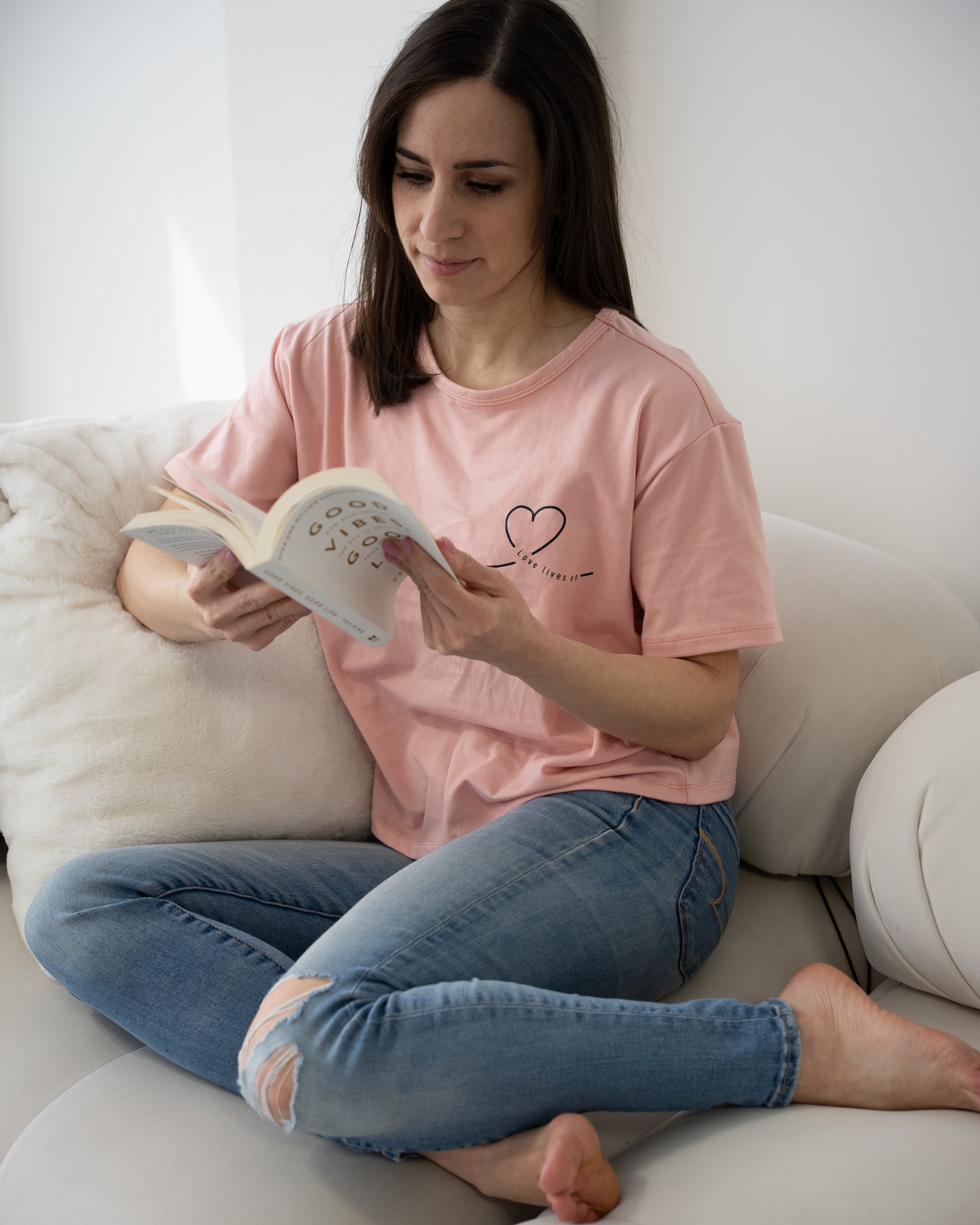 Founder reading a grief healing book while wearing HeartWear Co.’s pink Love Loungewear T-shirt — a peaceful moment of self-care