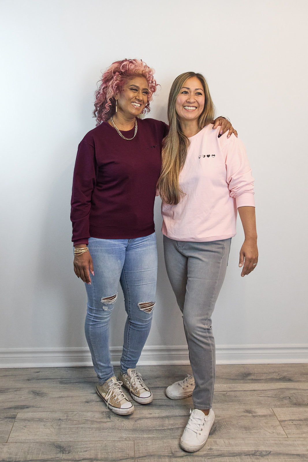 Two women wearing HeartWear Co. Heart Sweaters in pink and raspberry — comfort clothing that connects and supports healing.
