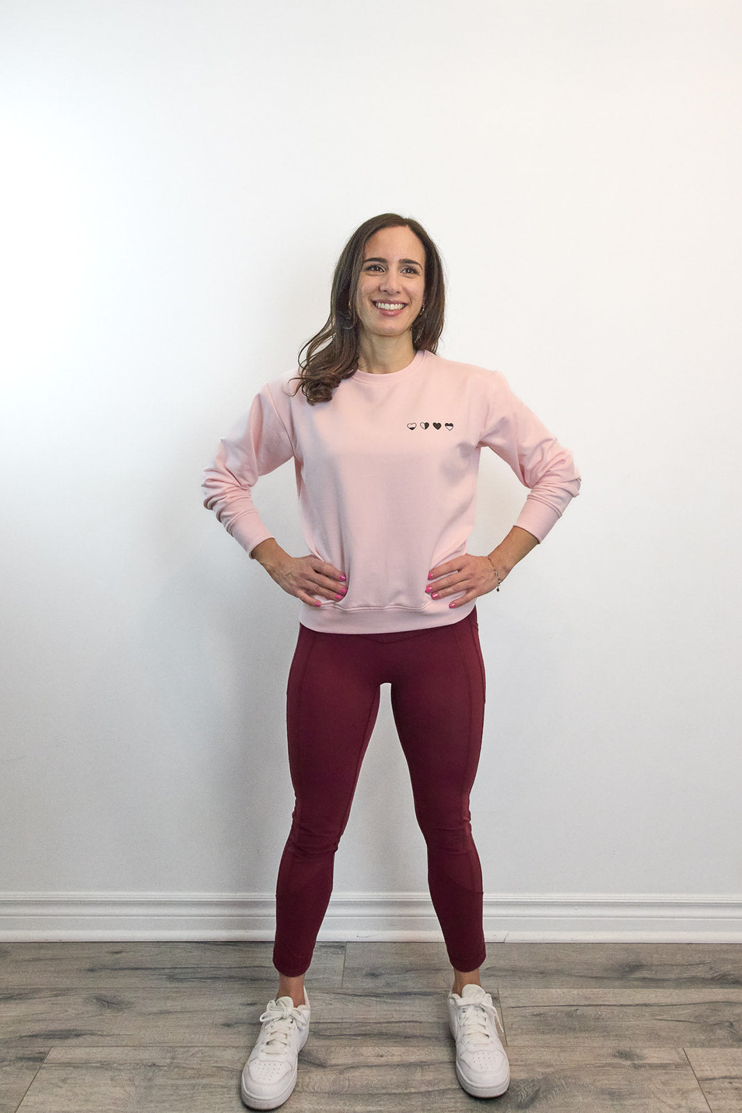 Woman standing hands on hips wearing pink Heart Sweater with four hearts—every emotion is valid.