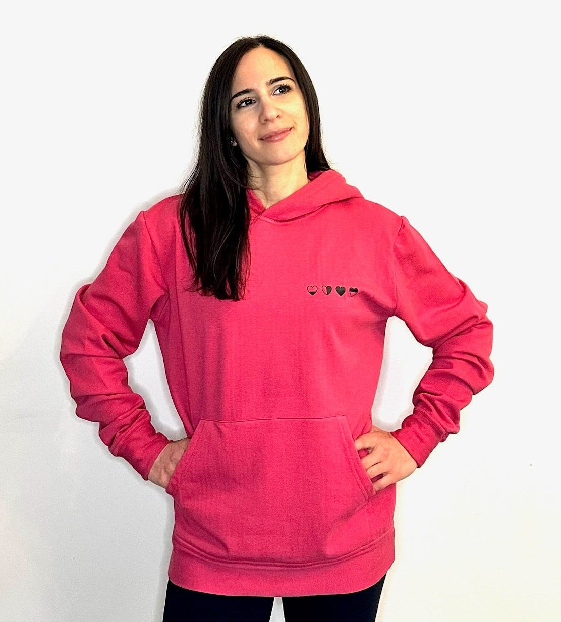 Person wearing a pink hoodie with a small logo on a white background