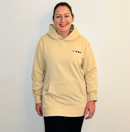 Person wearing a beige hoodie with a logo on a plain background