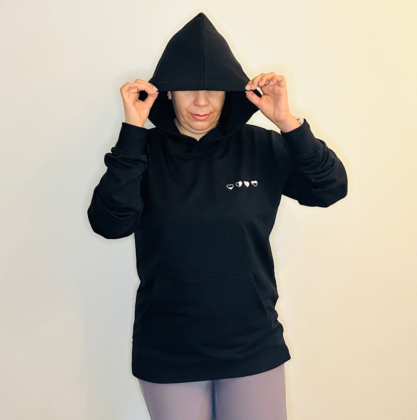 Person wearing a black hoodie with a logo on a plain background