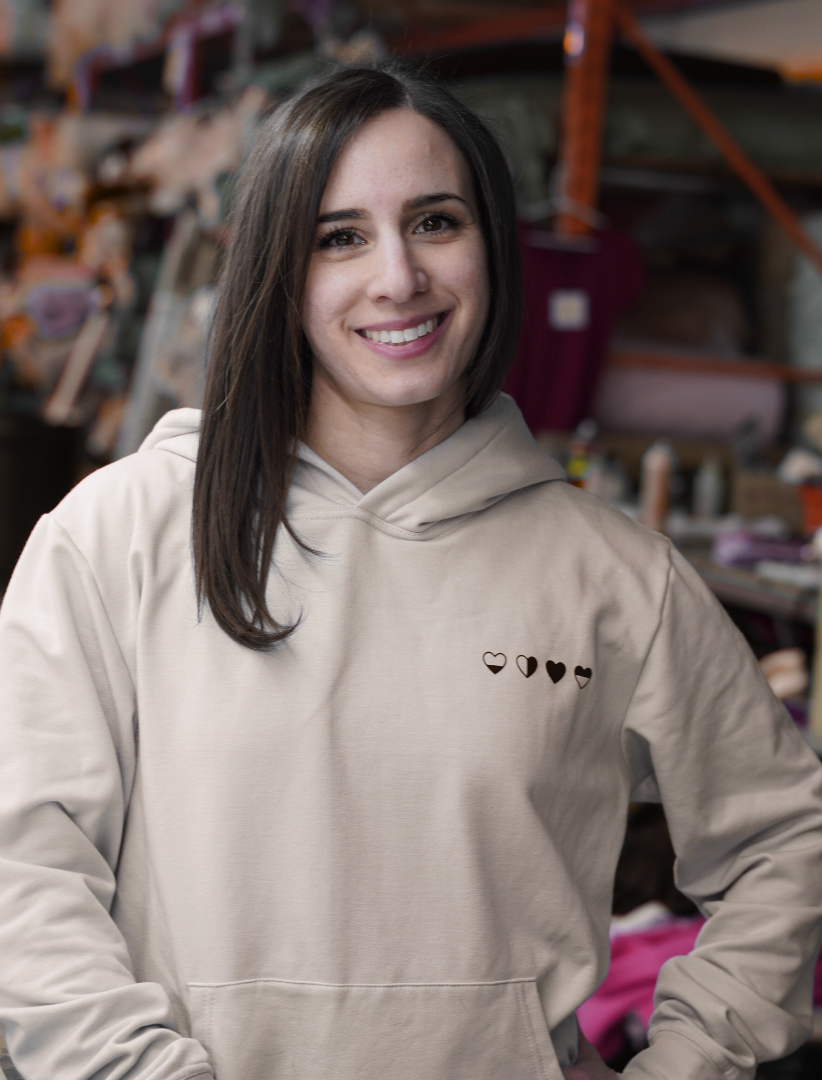 Woman wearing a beige hoodie with heart designs in the manufacturing