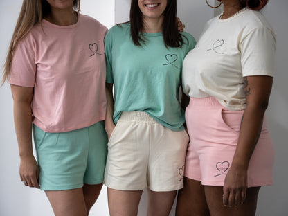 Three women wearing Love Loungewear T-shirt and shorts in natural, pink, and pistachio – emotional healing apparel