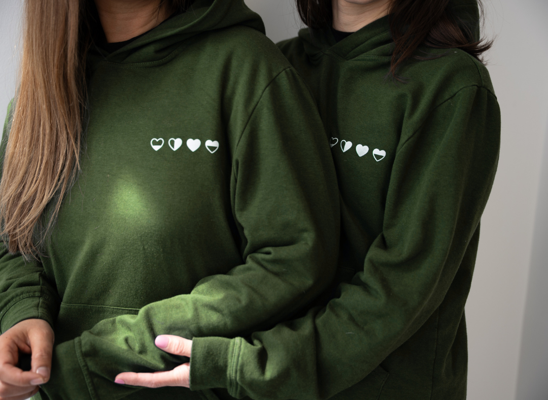 Two women wearing hearts hoodies in green 