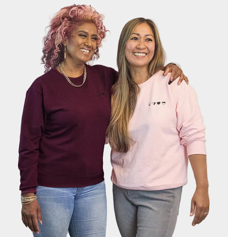 Two women wearing HeartWear Co. Heart Sweaters in pink and raspberry — comfort clothing that connects and supports healing.