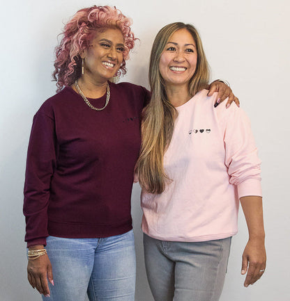 Two women wearing HeartWear Co. Heart Sweaters in pink and raspberry — comfort clothing that connects and supports healing.