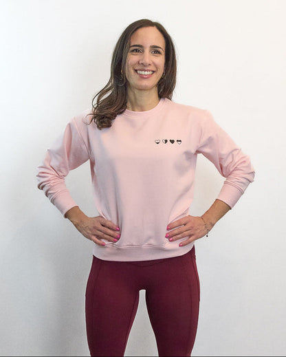 Woman standing hands on hips wearing pink Heart Sweater with four hearts—every emotion is valid.